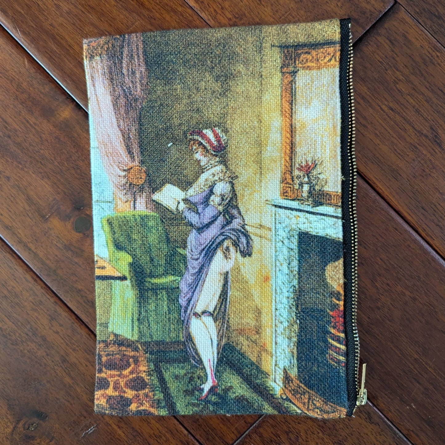 Large zipper pouch printed a woman reading and also lifting her skirt in the back, revealing her bare bum, to warm by the fire in a living room. From the 19th century with a purple dresses and brightly colored room. Virgil's Fine Goods