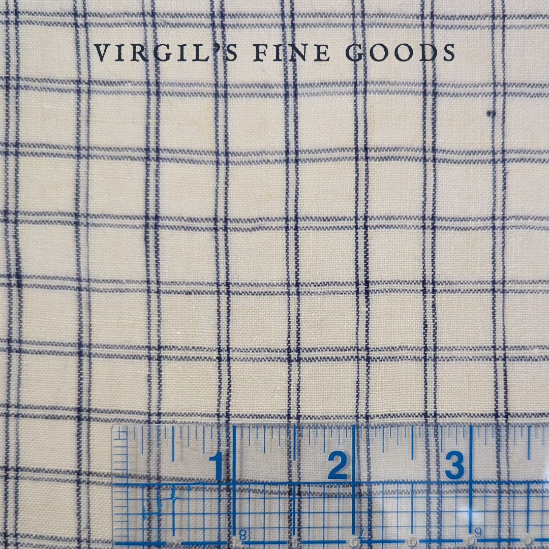Blue and white checked linen fabric Laid flat with a inch-ruled ruler on the bottom to show the scale of the checked pattern. With the words: "Virgil's Fine Goods"