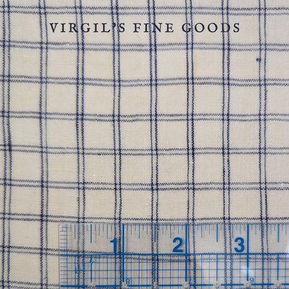 Blue and white checked linen fabric Laid flat with a inch-ruled ruler on the bottom to show the scale of the checked pattern. With the words: "Virgil's Fine Goods"