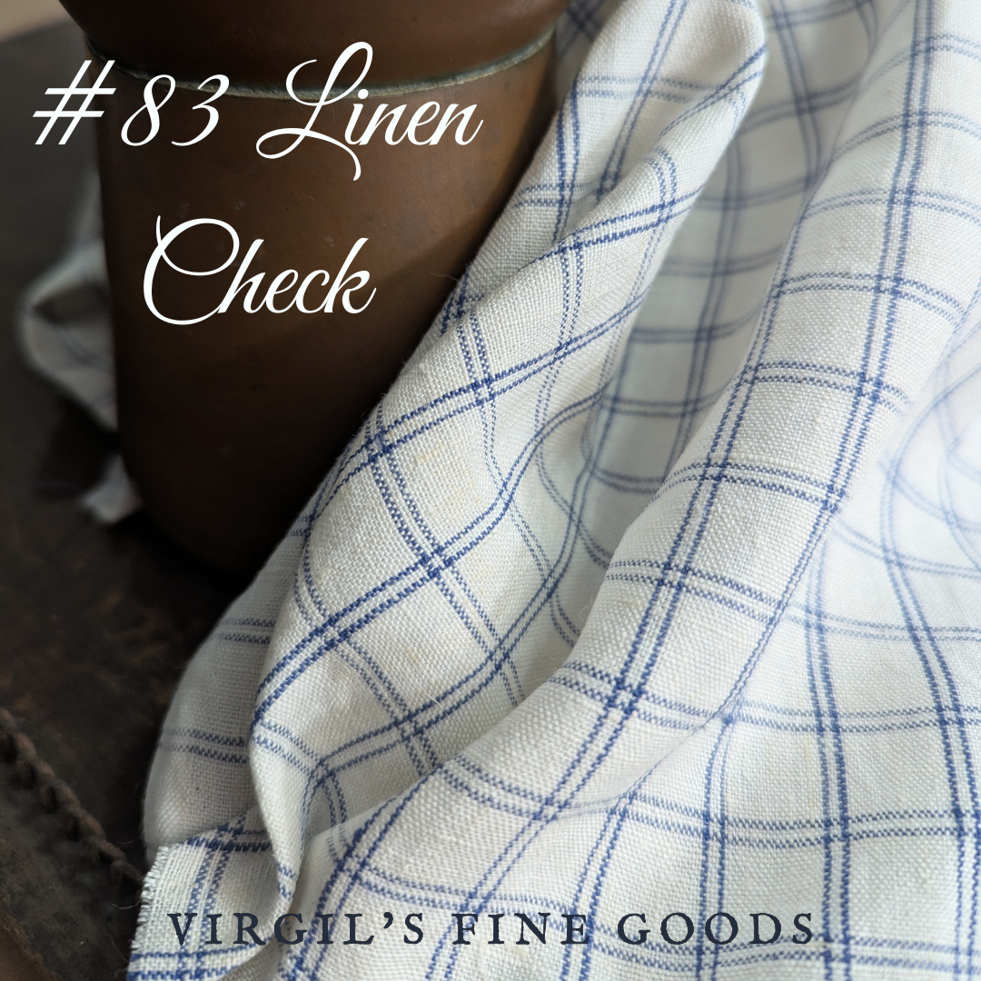 Blue and white checked linen fabric gently draped over a copper pot with the words: "#83 Linen Check" and "Virgil's Fine goods"