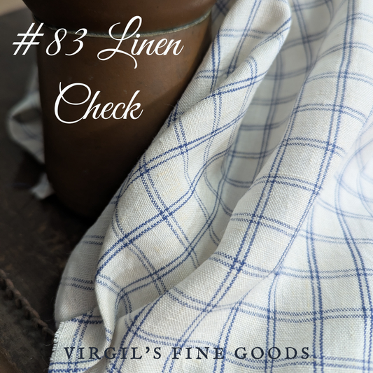Blue and white checked linen fabric gently draped over a copper pot with the words: "#83 Linen Check" and "Virgil's Fine goods"