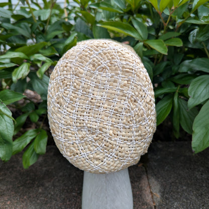 Top view of Crown for Tan and white Straw bonnet with squared crown and open brim for regency era to show different colors. Background of green peony leaves. VirgilsFineGoods.com