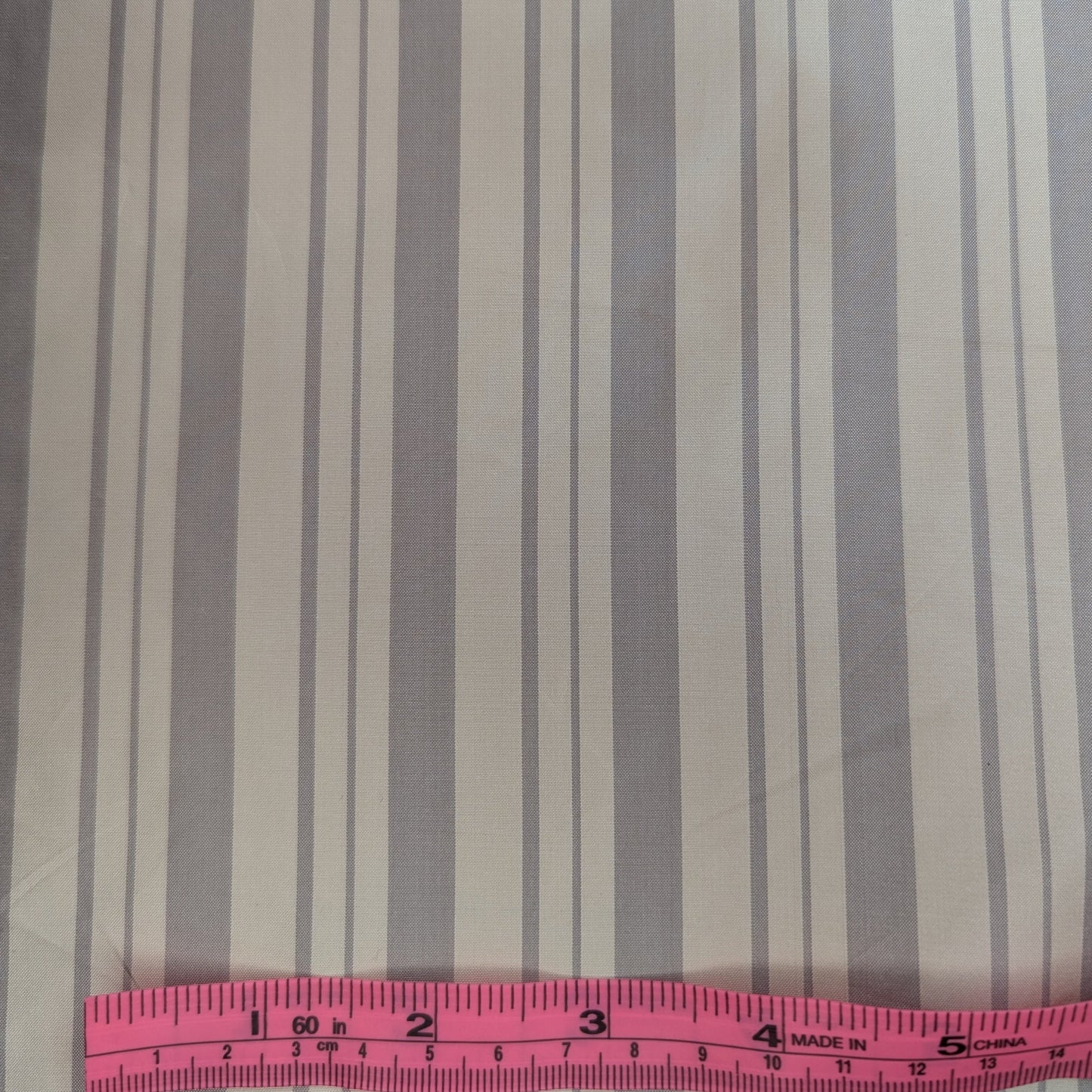 Off-white background with gray stripe woven into fabric. Yarn dyed silk. Photographed with a pink ruler to illustrate pattern scale.