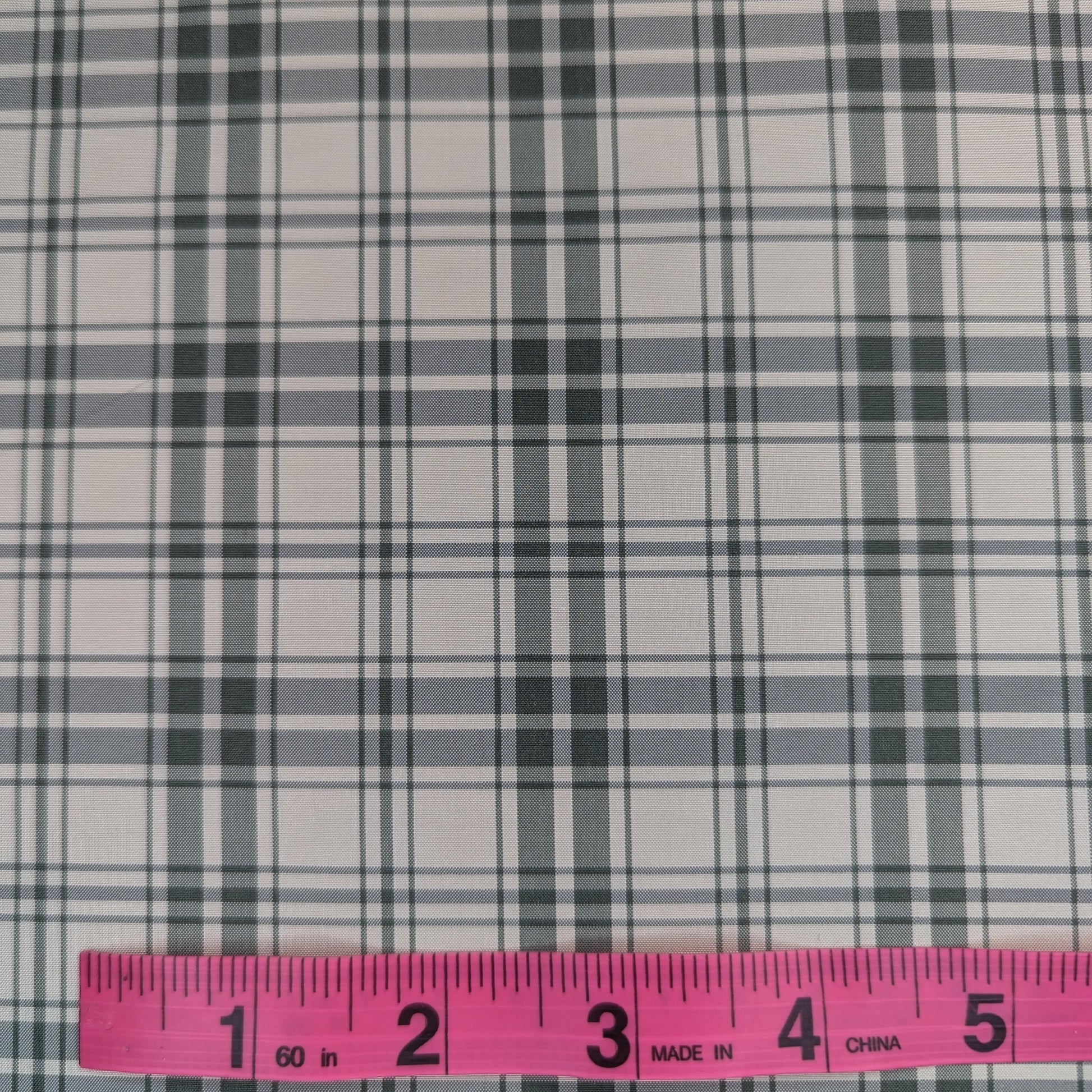 Off-white background with green plaid pattern woven into fabric. Yarn dyed silk. Photographed with a pink ruler to illustrate pattern scale.