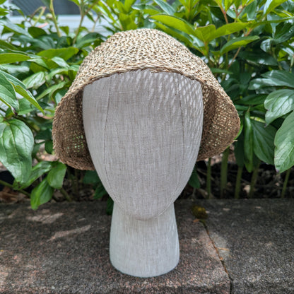 Tan Open-weave Straw bonnet with short brim rounded crown for early regency era. Background of green peony leaves. VirgilsFineGoods.com
