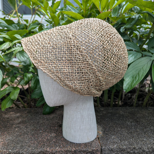 Tan Open-weave Straw bonnet with short brim rounded crown for early regency era. Background of green peony leaves. VirgilsFineGoods.com