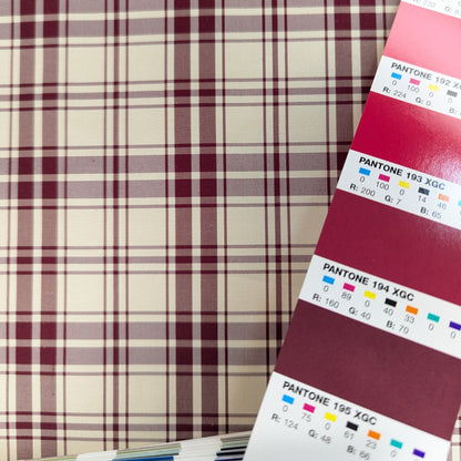 Off-white background with red plaid pattern woven into silk fabric. Yarn dyed silk. Photographed with a pantone chips for color matching