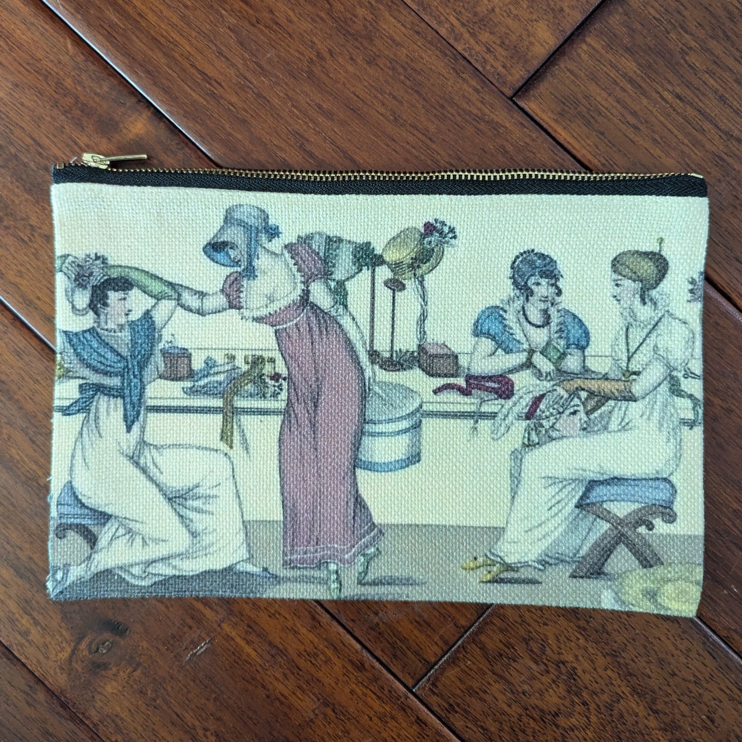 Pouch printed with 4 women from the 19th century with several women trying on hats in a shop. Virgil's Fine Goods