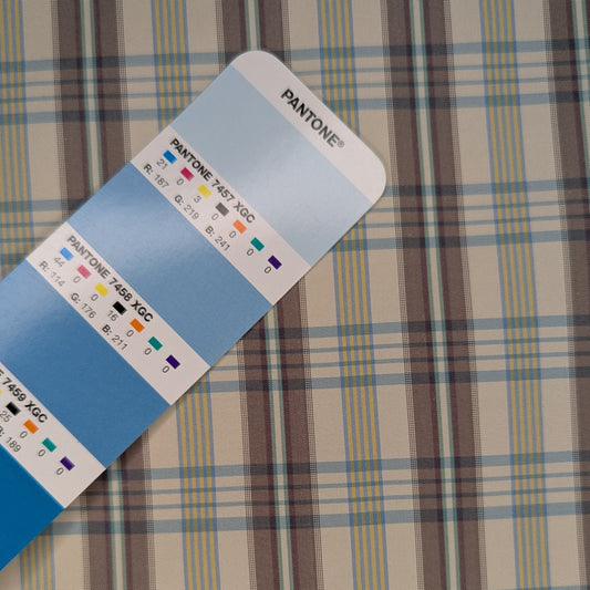 Off-white background with multicolored plaid pattern woven into fabric. Yarn dyed silk. Photographed with a blue pantone chip for reference and color matching.