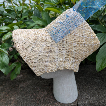 Side View Tan and white Straw bonnet with squared crown and open brim for regency era, being measured by a ruler showing a 4" high crown. Background of green peony leaves. VirgilsFineGoods.com