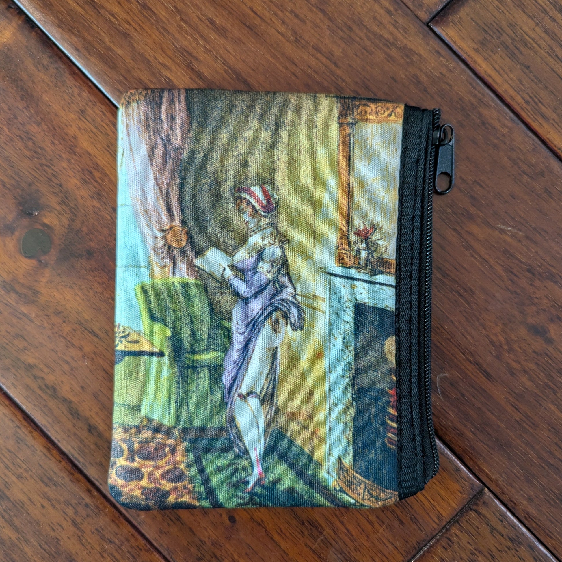 Small zipper pouch printed a woman reading and also lifting her skirt in the back, revealing her bare bum, to warm by the fire in a living room. From the 19th century with a purple dresses and brightly colored room. Virgil's Fine Goods