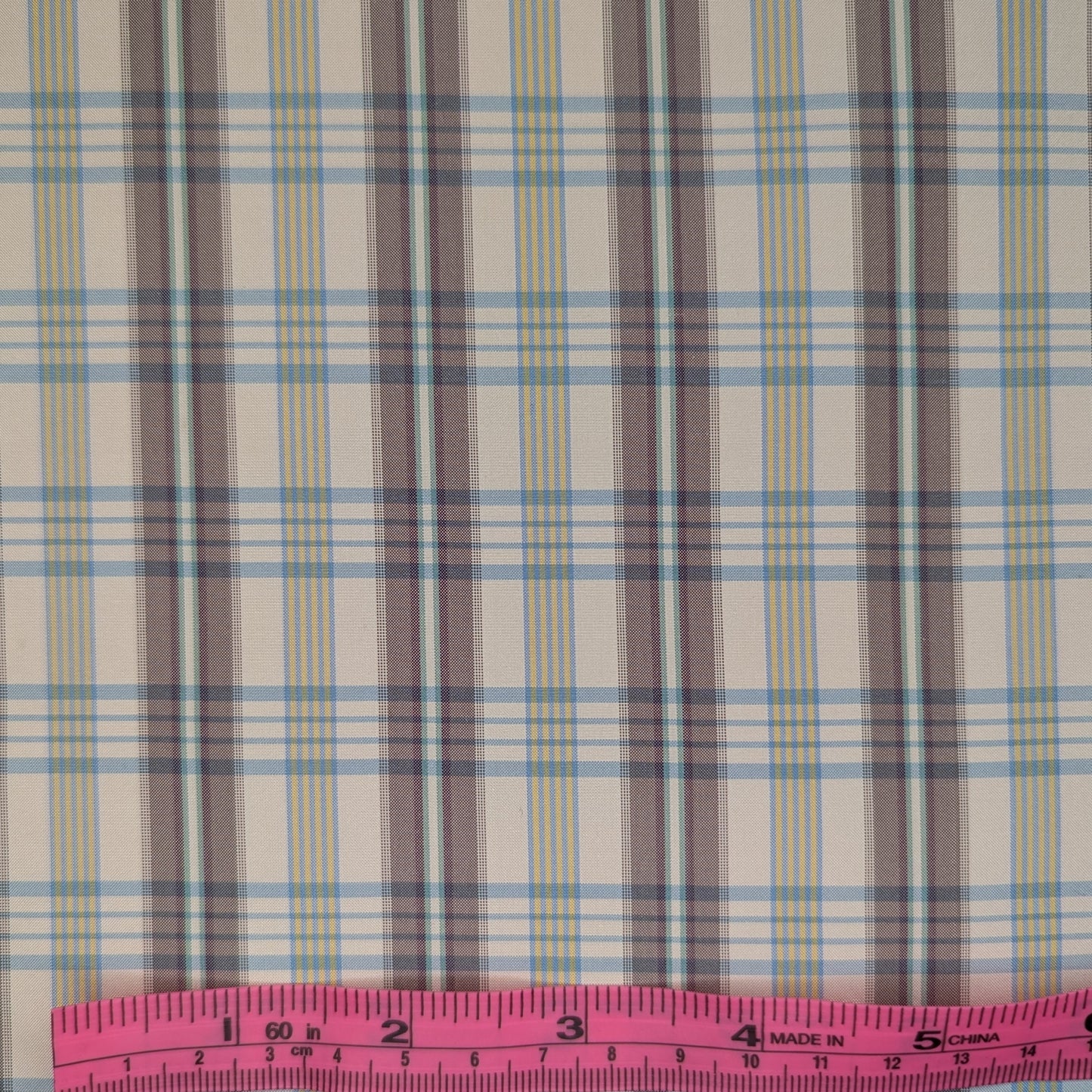 Off-white background with multicolored plaid pattern woven into fabric. Yarn dyed silk. Photographed with a pink ruler to illustrate pattern scale.
