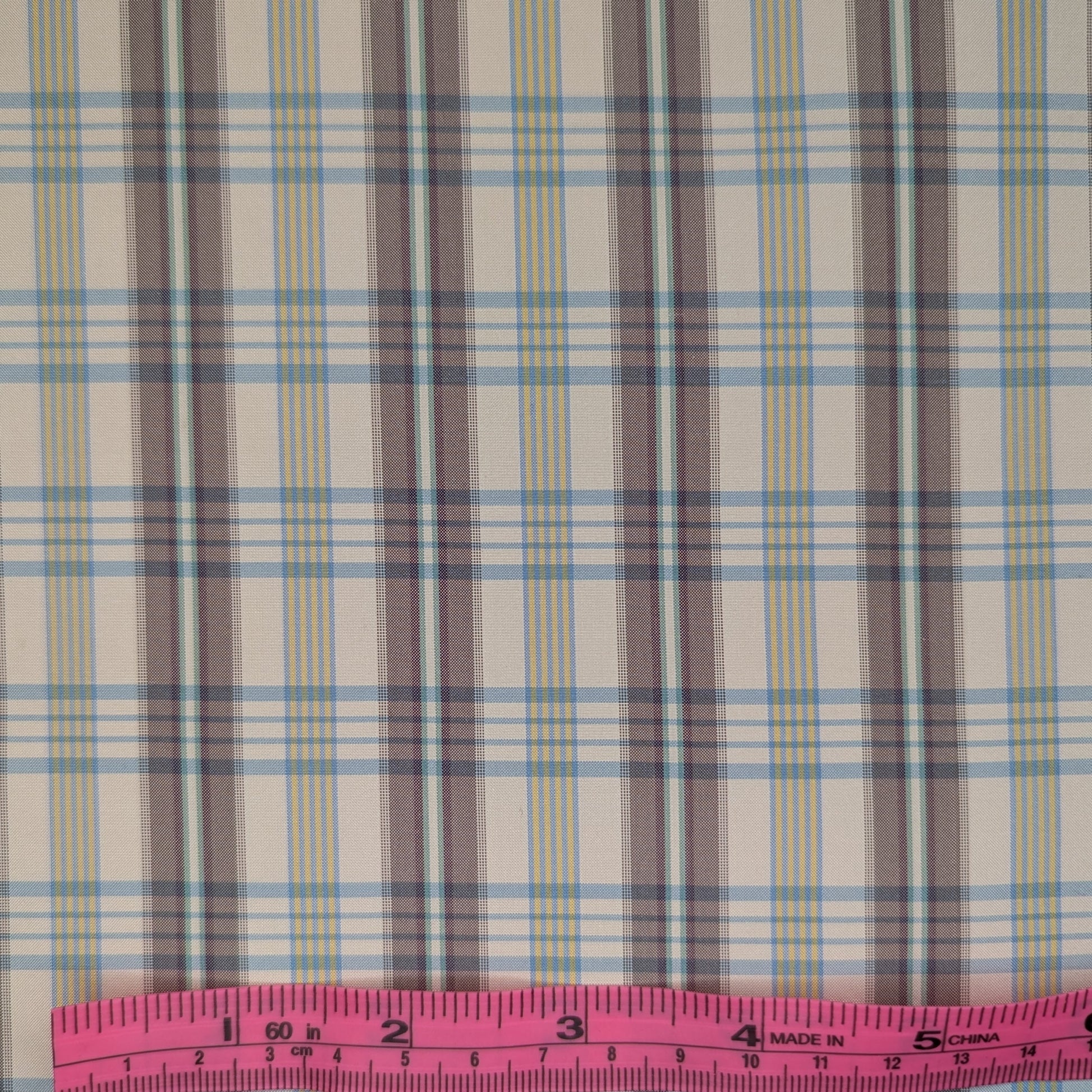 Off-white background with multicolored plaid pattern woven into fabric. Yarn dyed silk. Photographed with a pink ruler to illustrate pattern scale.